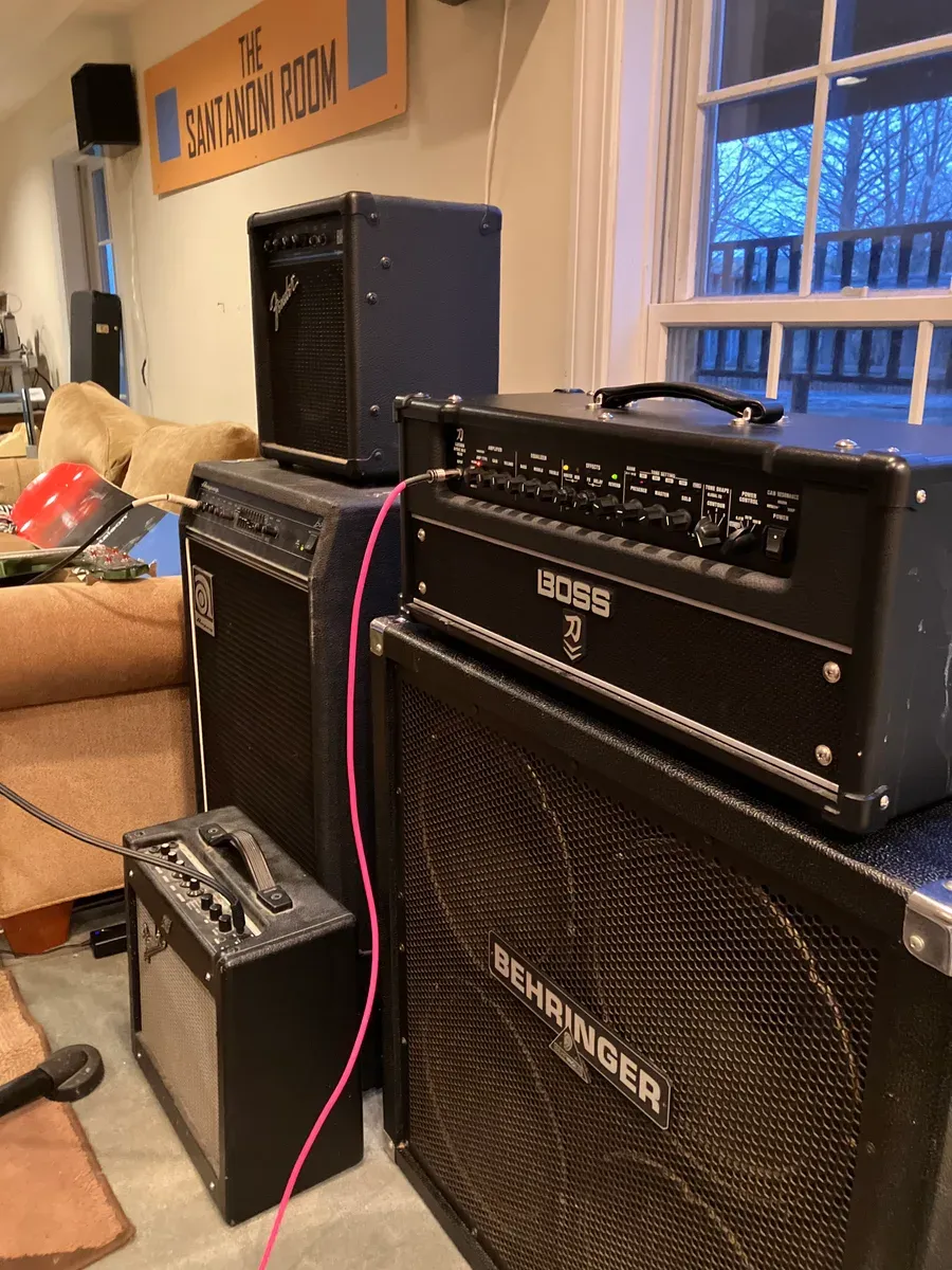 A Boss amp head on a Behringer 4x12 cabinet, with an Ampeg, a Fender combo and a practice amp alongside.