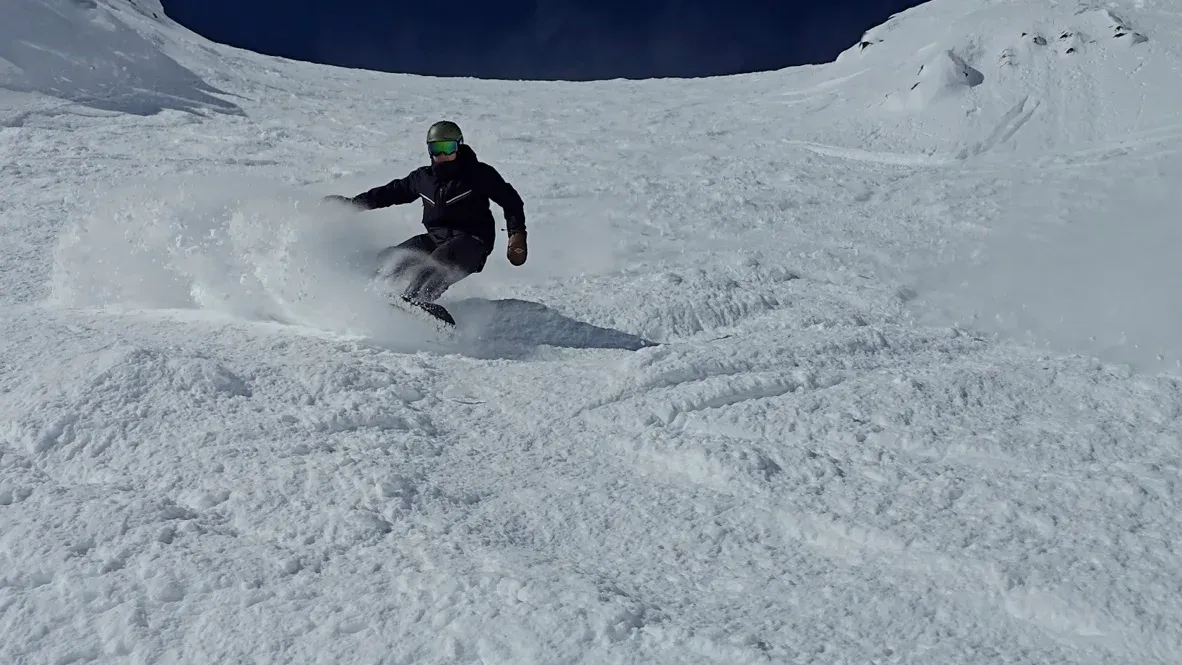 Andrew carving a turn through soft snow, spray coming off the board.